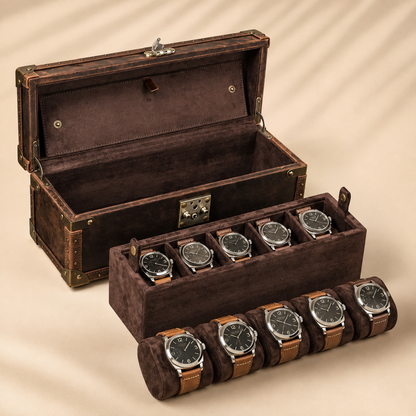 Plateau amovible avec 5 montres et 5 montres posées sur coussin devant la malle vide