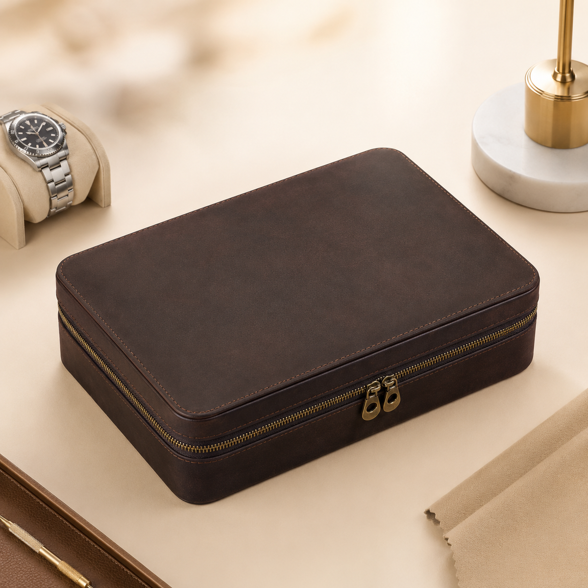 Étui à montres en cuir nubuck marron fermé, sur bureau avec une montre posée à côté